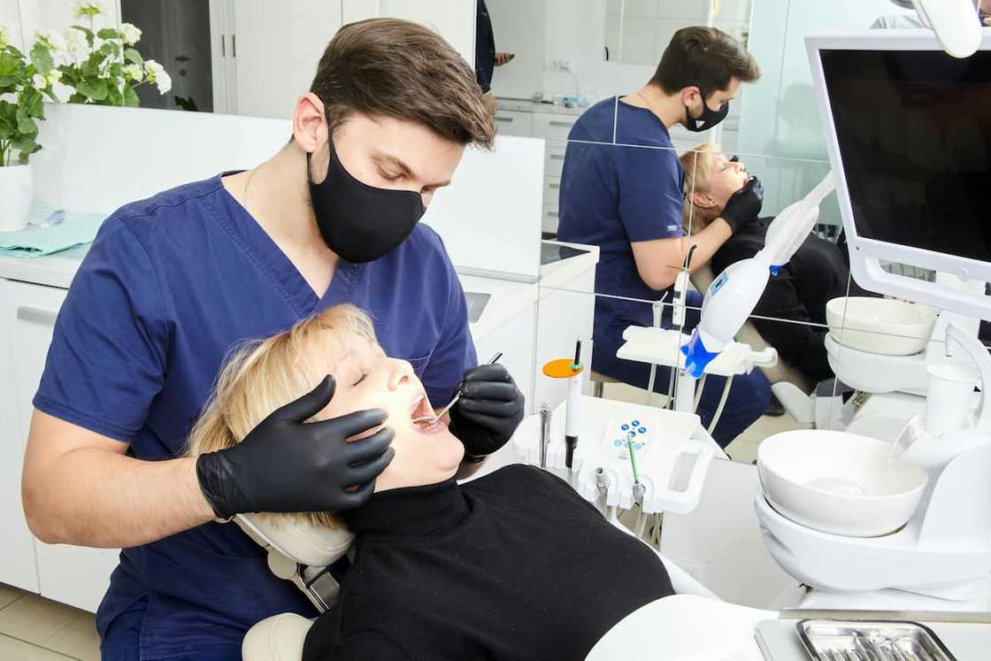 A male medic doing a dental procedure on a female patient A male medic doing a dental procedure on a female patient