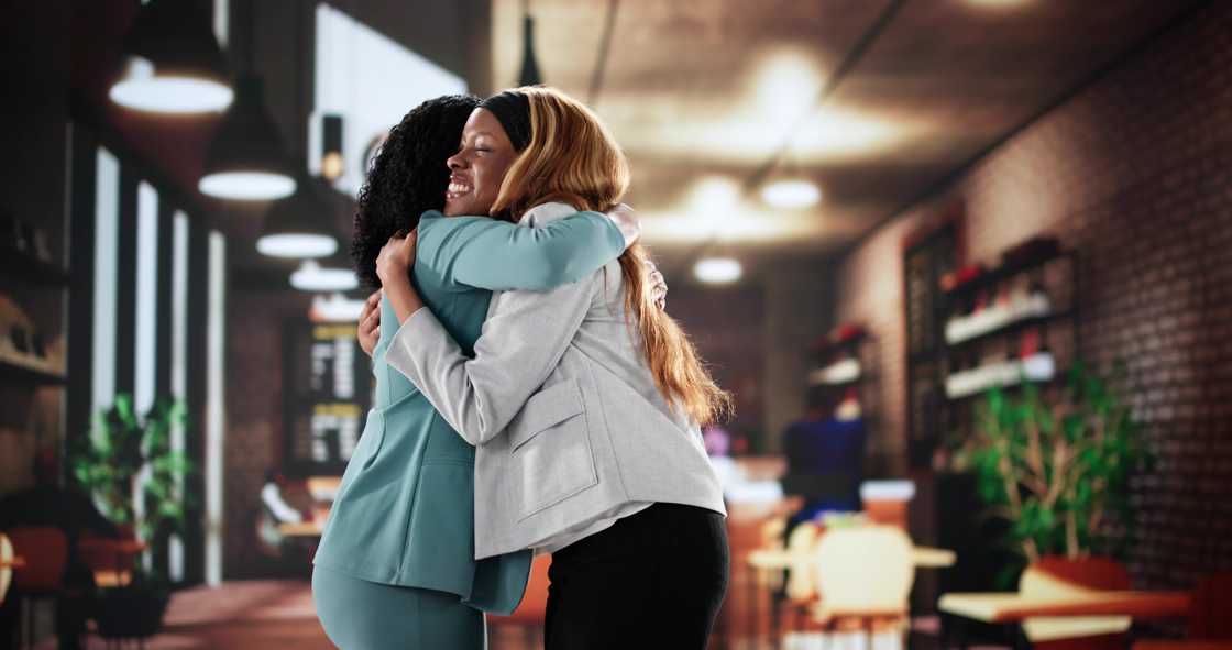Two women hugging each other in coffee shop.