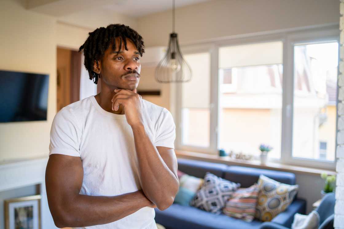 A man looking away from the camera, holding one hand to his neck A man looking away from the camera, holding one hand to his neck
