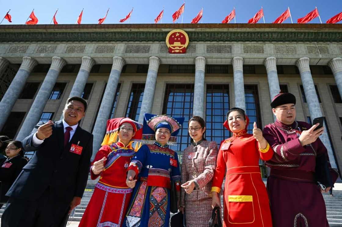 The traditional dress of China's ethnic minority groups punctuated a sea of monochrome suits The traditional dress of China's ethnic minority groups punctuated a sea of monochrome suits