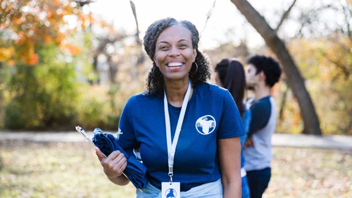Portrait of a woman is leading a group of volunteering during a community cleanup day. Portrait of a woman is leading a group of volunteering during a community cleanup day.