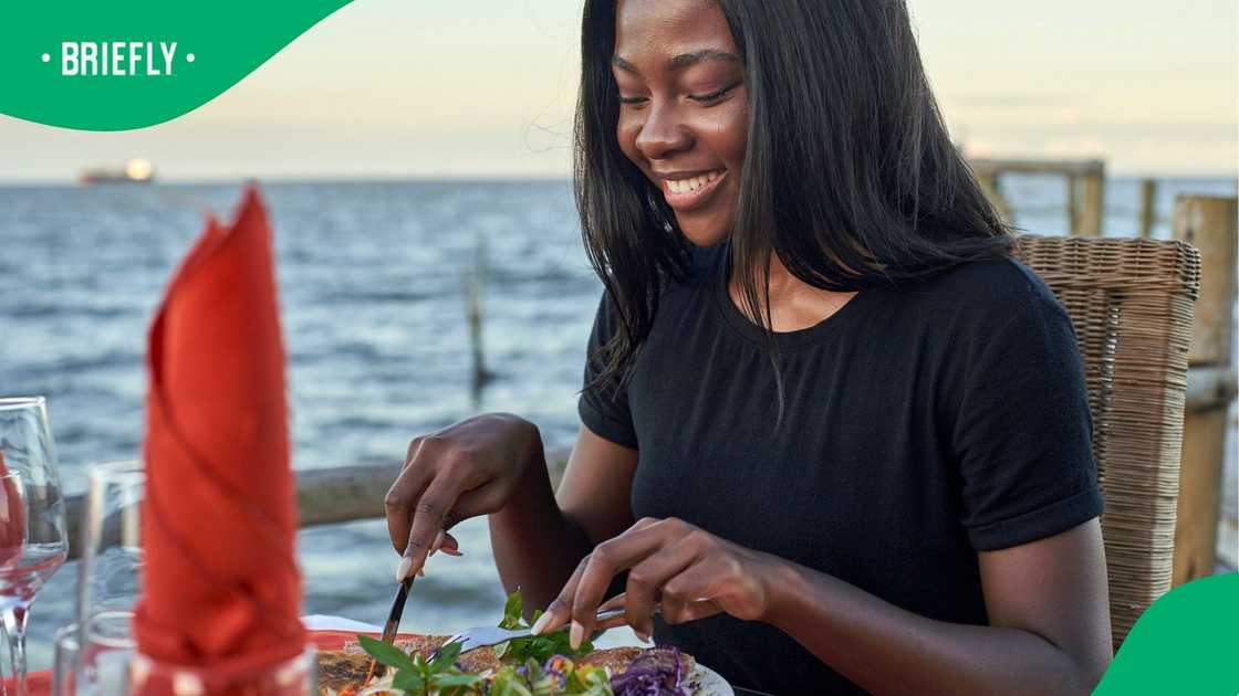 A young woman at a Maputo waterfront enjoying dinner.