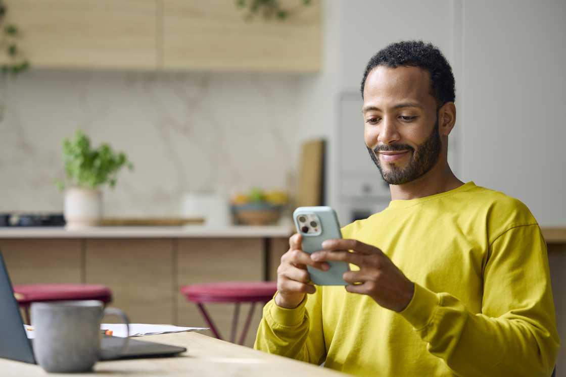 A man sitting at a table and looking at his phone. A man sitting at a table and looking at his phone.
