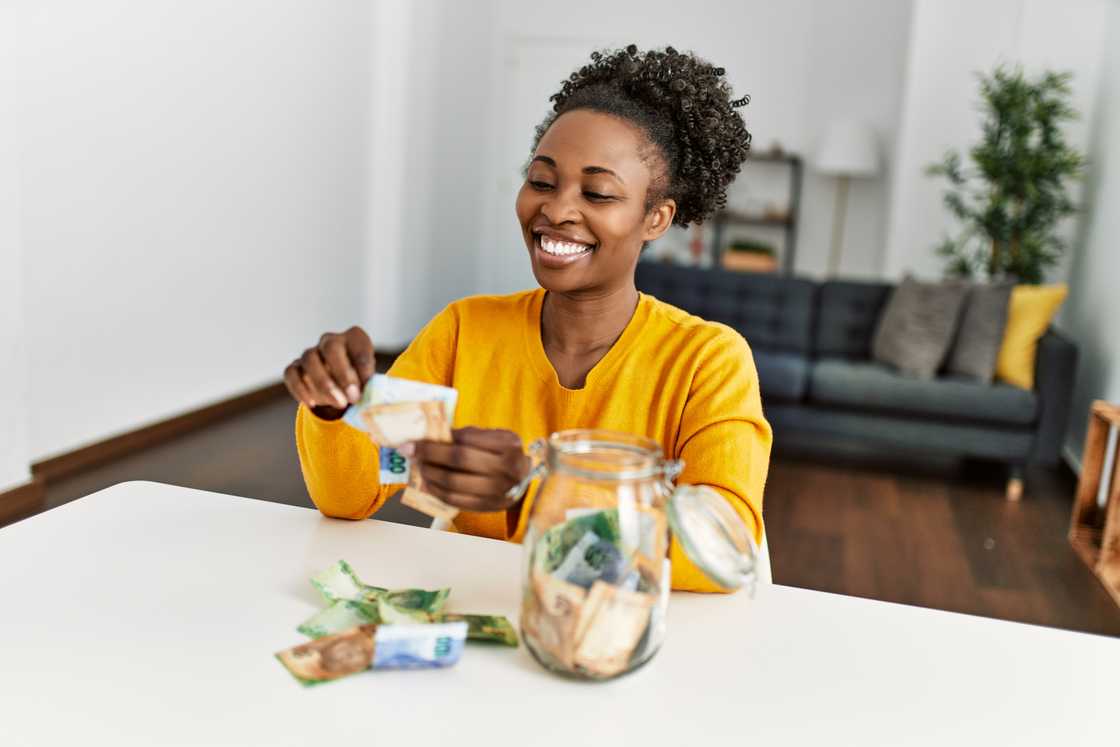 A stock photo woman sitting on table holding rand banknotes