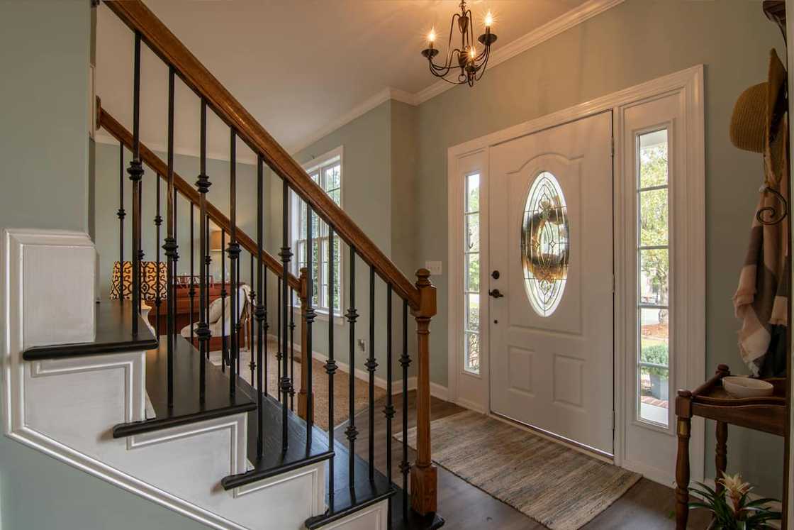 A brown wooden staircase with a brass chandelier