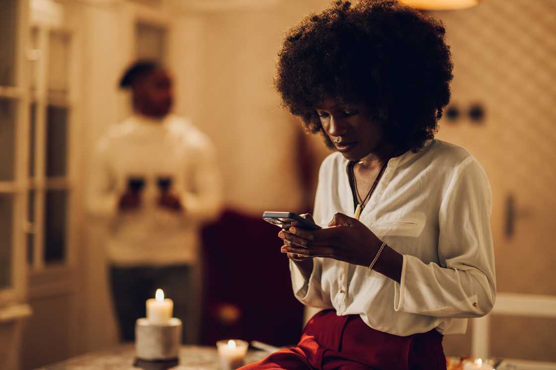 A woman looks at her phone at the hallway.