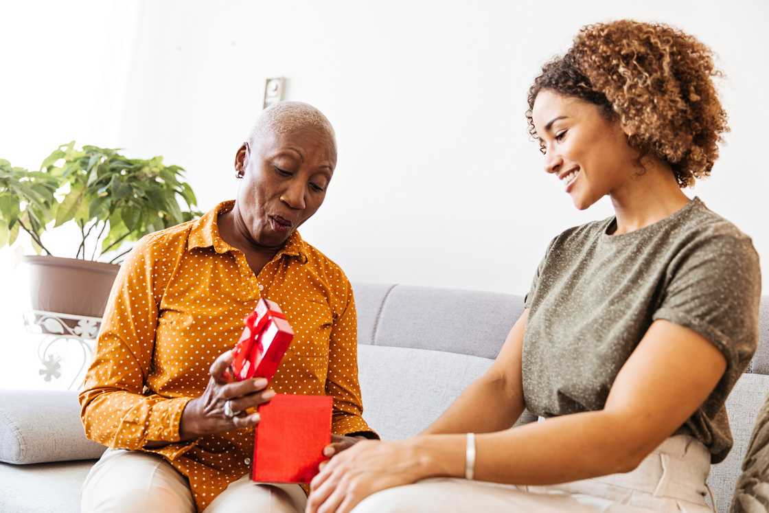 A daughter gives her grandmother a gift cared. A daughter gives her grandmother a gift cared.