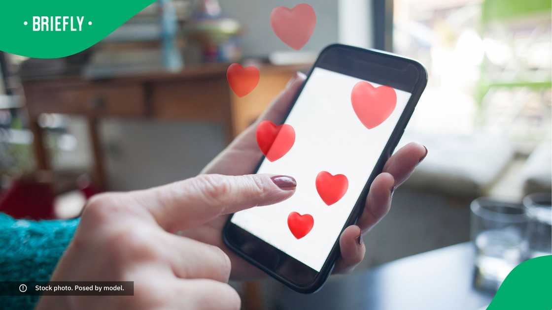 A woman typing on a phone with hearts coming out.