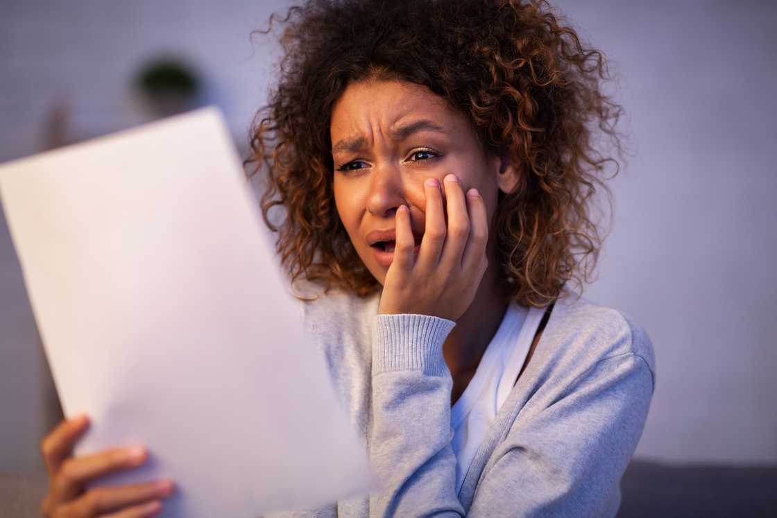 A disappointed woman reading letter of break up from boyfriend