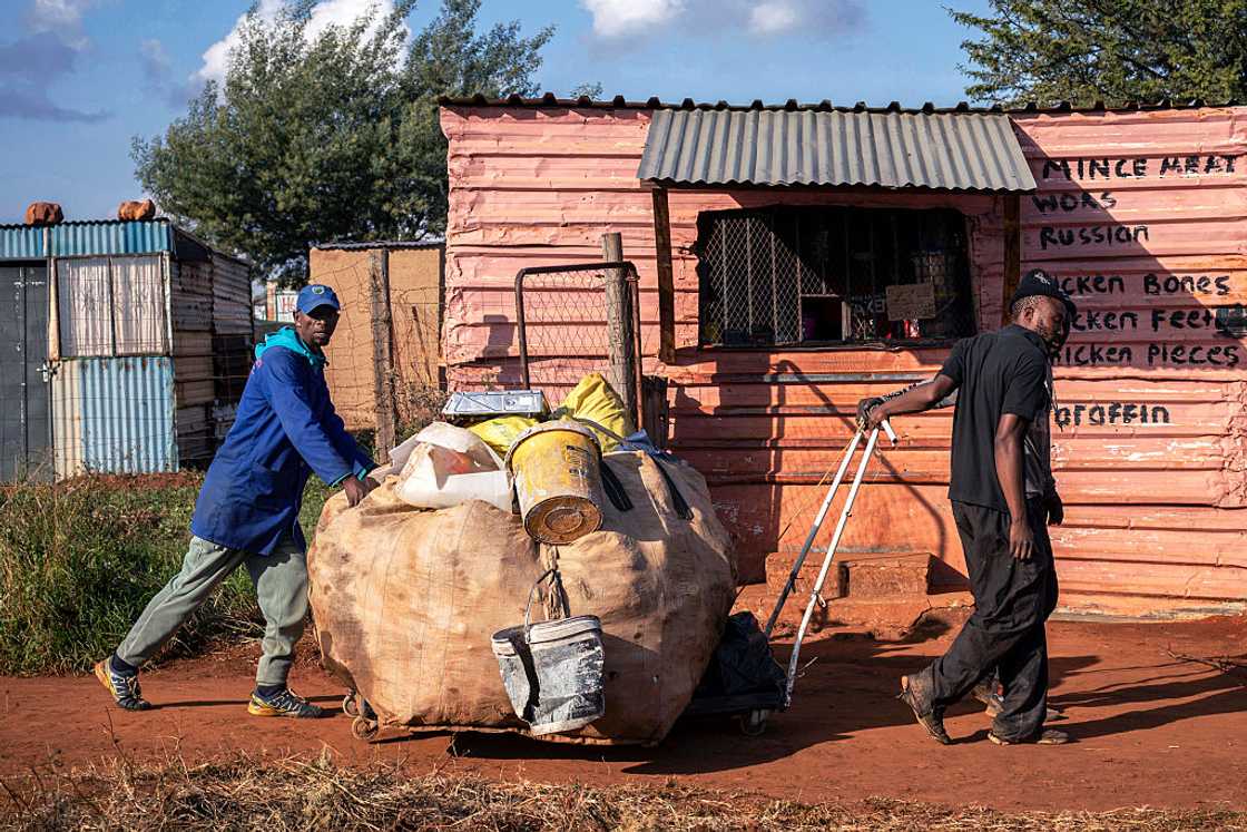 Men push a cart with recycled goods in front of a local spaza shop in an informal settlement on May 4, 2026 in Mountain City south of Johannesburg, South Africa Men push a cart with recycled goods in front of a local spaza shop in an informal settlement on May 4, 2026 in Mountain City south of Johannesburg, South Africa