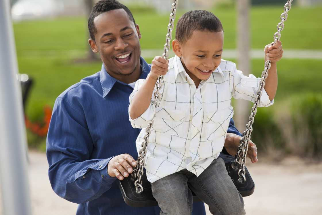 A man pushes a child on a swing.
