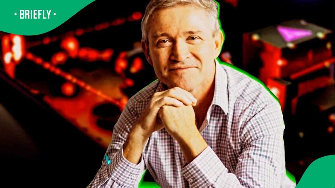 The man posed thoughtfully with folded hands, highlighted by bright lighting and a vivid backdrop. The man posed thoughtfully with folded hands, highlighted by bright lighting and a vivid backdrop.