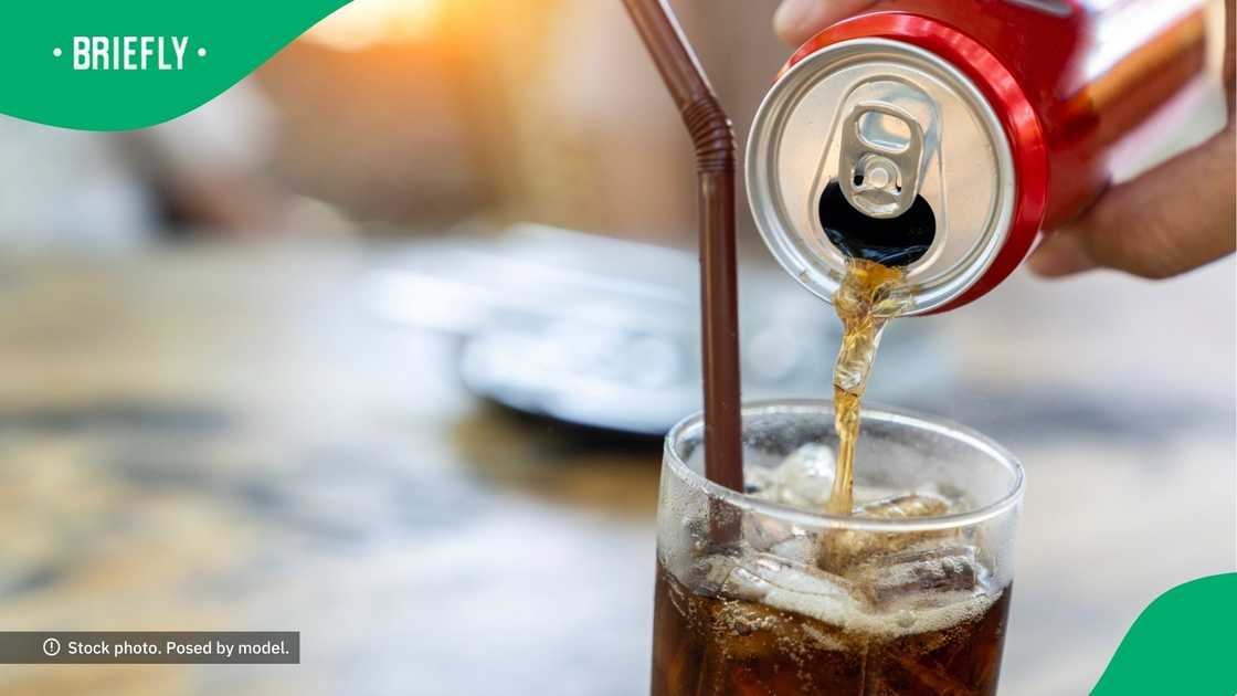 A person throwing Coca-Cola into a glass.