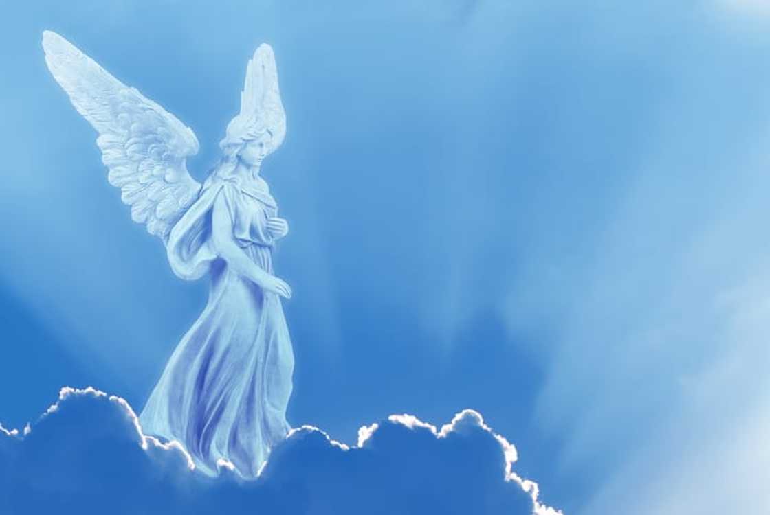 An angel on a white cloud against a clear blue sky with copy space