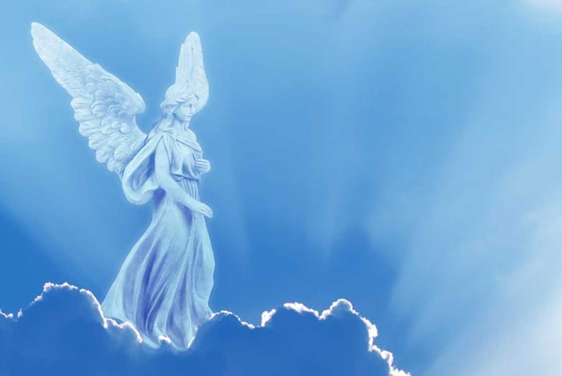 An angel on a white cloud against a clear blue sky with copy space An angel on a white cloud against a clear blue sky with copy space