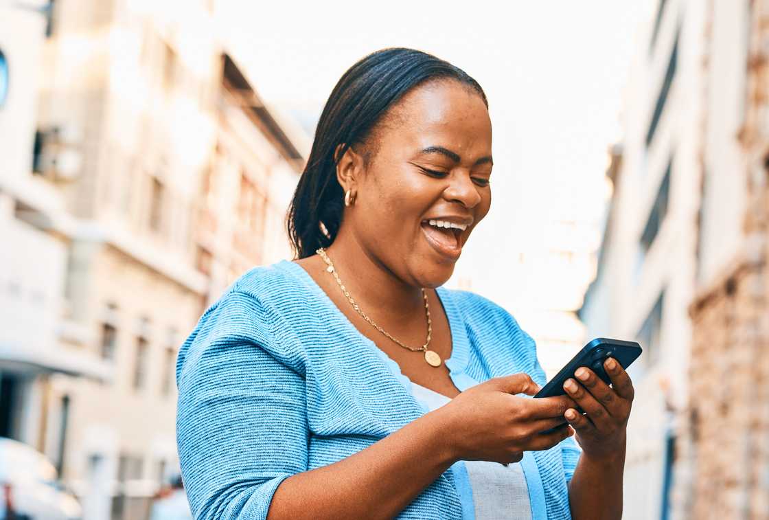 A woman smiles at her phone. A woman smiles at her phone.