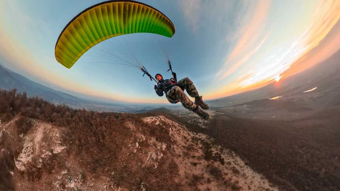 A man paragliding at sunset.