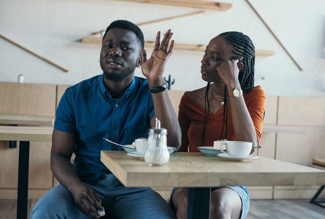 A man confronts a woman in a café setting.