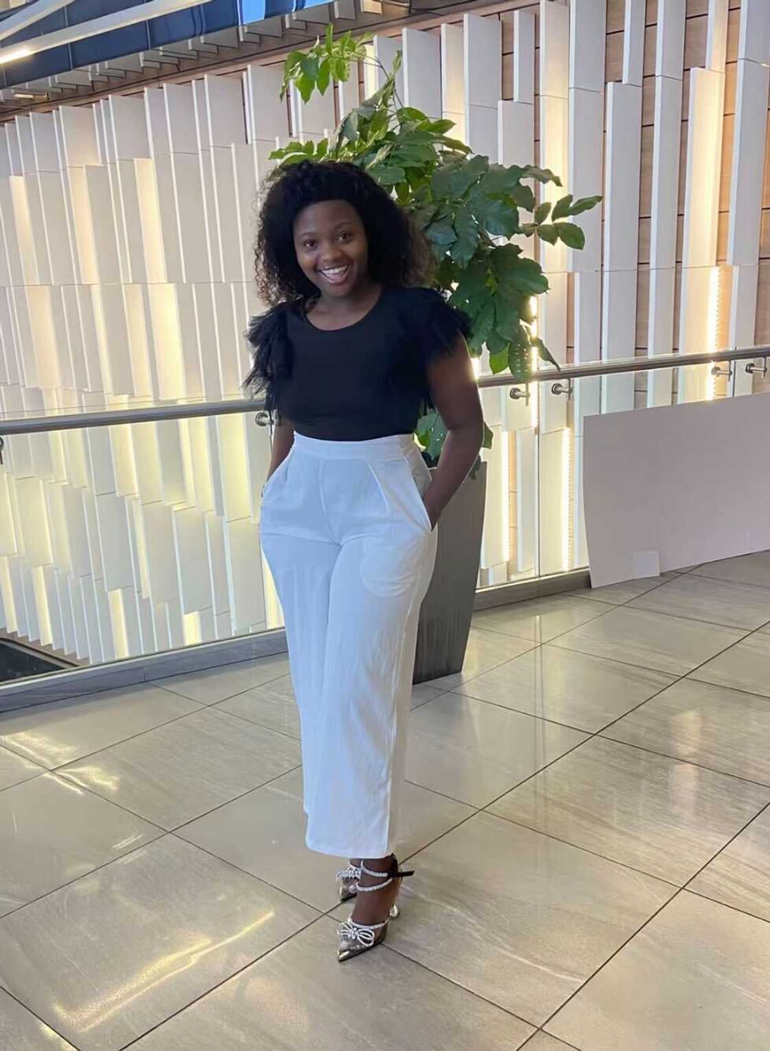 A woman posed in a TikTok video dressed in white pants and a top.