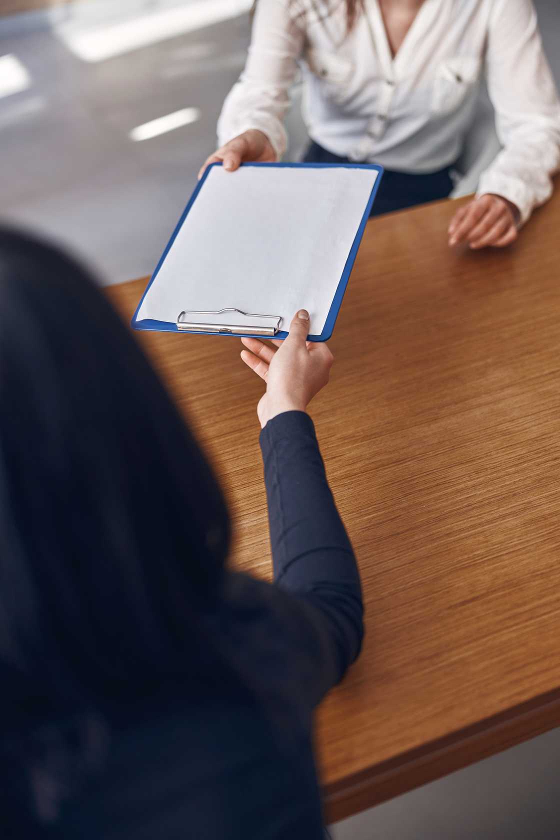 A person hands over a clipboard to a woman A person hands over a clipboard to a woman
