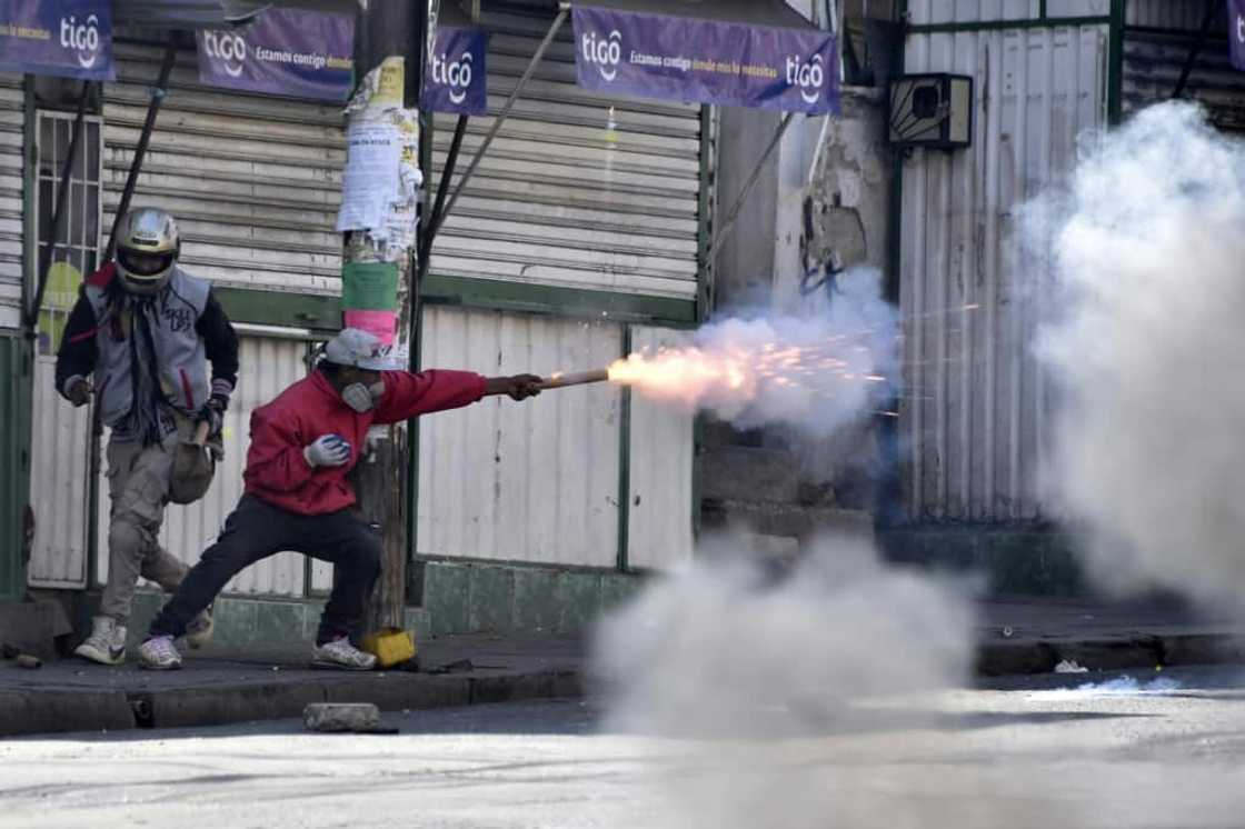 A Bolivian protester throws firecrackers at police officers during a protest march by coca leaf growers in La Paz, on August 2, 2022 A Bolivian protester throws firecrackers at police officers during a protest march by coca leaf growers in La Paz, on August 2, 2022