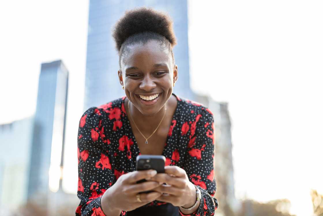 A woman smiles at her phone. A woman smiles at her phone.