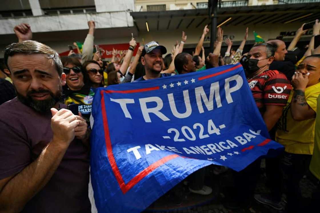 A supporter of Brazilian President Jair Bolsonaro, known as 'the Tropical Trump,' unfurls a pro-Trump flag at the president's re-election rally in Juiz da Fora, in Minas Gerias state in Brazil on August 16 2022 A supporter of Brazilian President Jair Bolsonaro, known as 'the Tropical Trump,' unfurls a pro-Trump flag at the president's re-election rally in Juiz da Fora, in Minas Gerias state in Brazil on August 16 2022