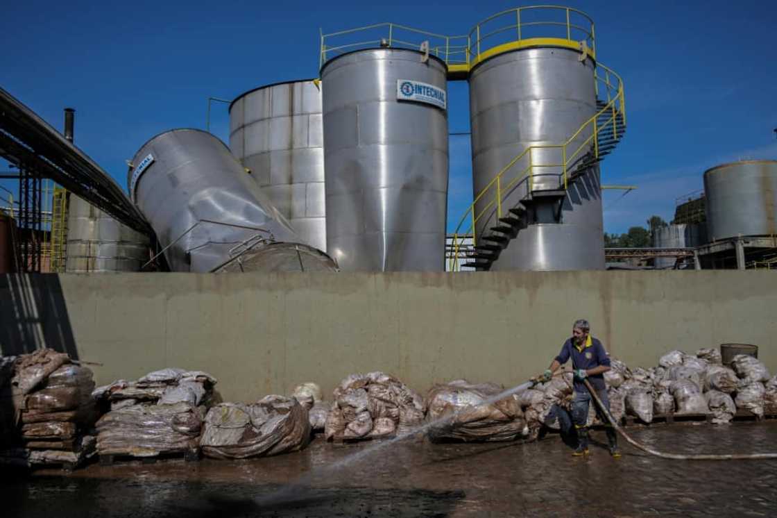 A worker uses a high pressure hose to remove mud accumulated by flooding at an industrial plant A worker uses a high pressure hose to remove mud accumulated by flooding at an industrial plant