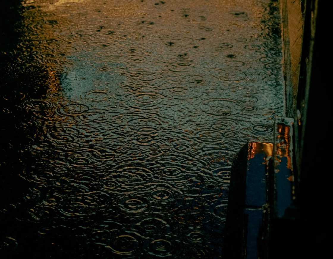 Rainwater ripples across a flooded street at night.