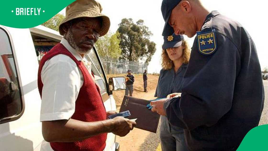 Police check the driver's licence of an elderly man
