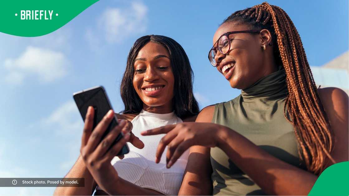 Two women laughing at a phone. Two women laughing at a phone.