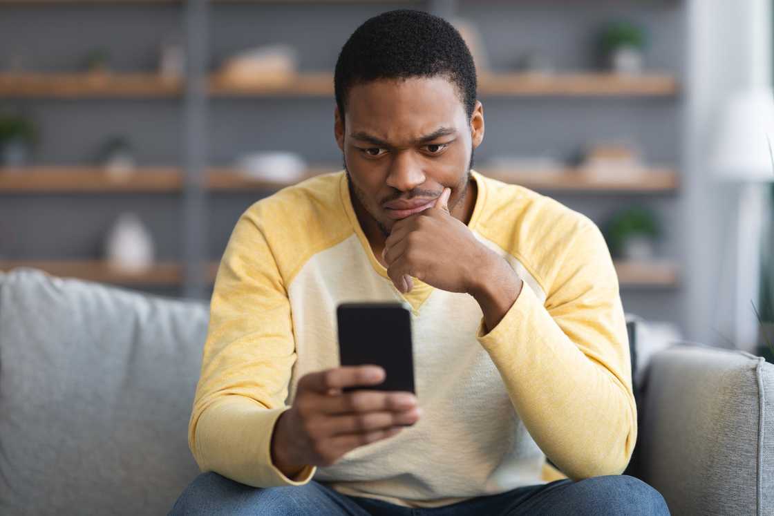 A man looking confused at his phone. A man looking confused at his phone.