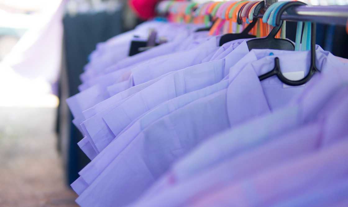 School uniforms displayed at a small roadside stall.