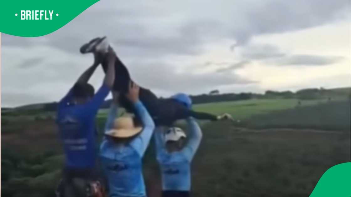 Staff members dressed in blue shirts held up a participant wearing a helmet right before they fell from the launch platform