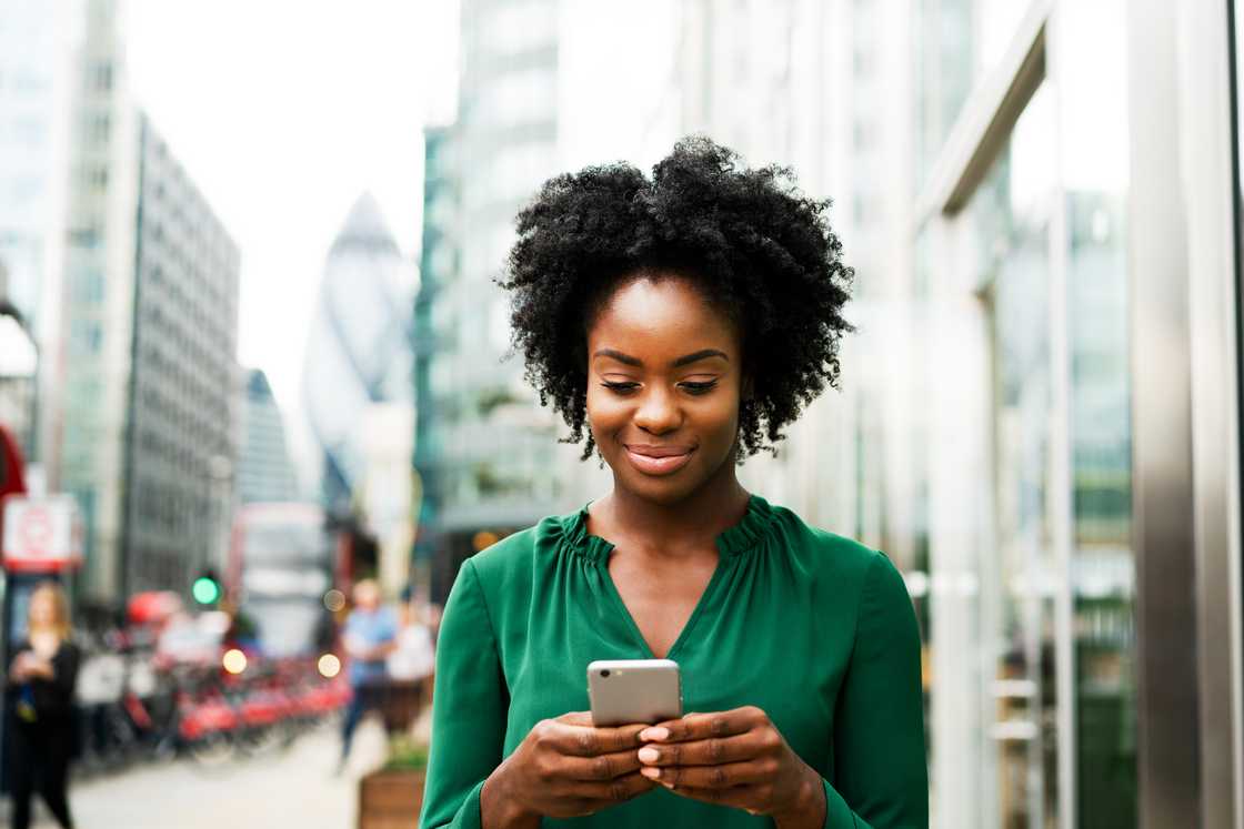 A woman smiling at her phone. A woman smiling at her phone.