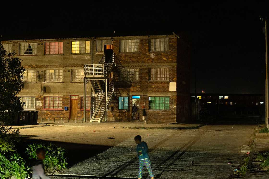 Children play outside a blocks of flats at night in Lavender Hill at night near Cape Town on August 28, 2025