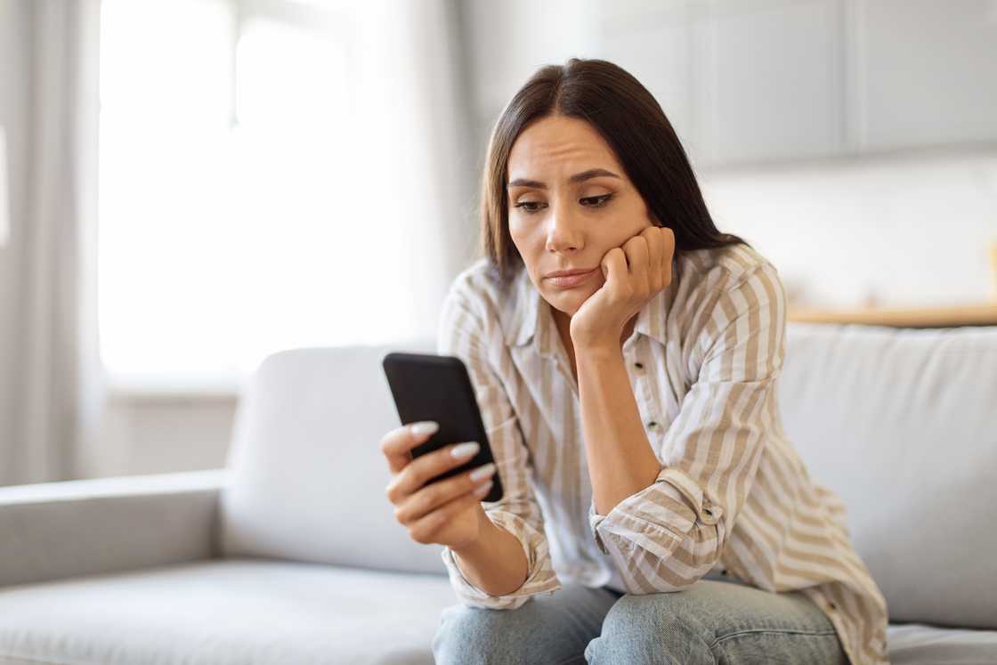 An upset woman looking at her phone.