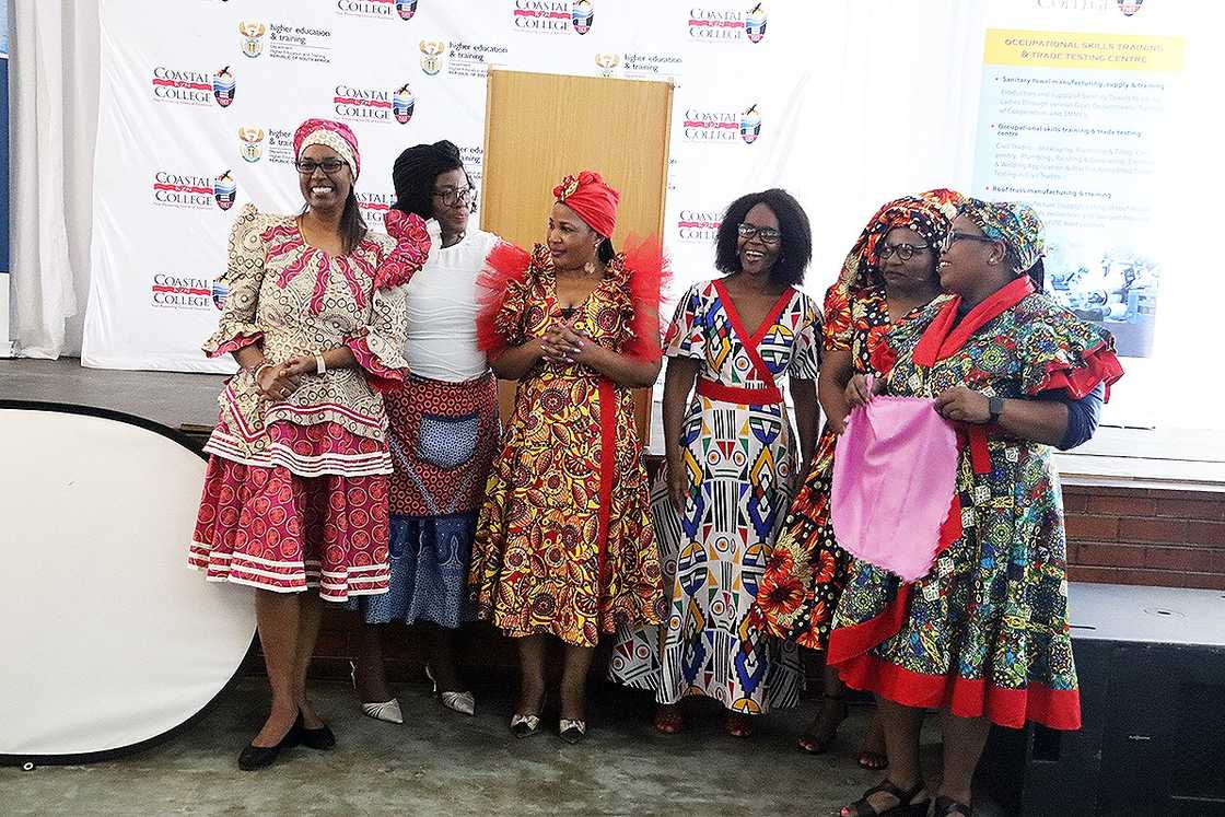 Women in colourful African outfits standing in front of a Coastal KZN TVET College banner Women in colourful African outfits standing in front of a Coastal KZN TVET College banner