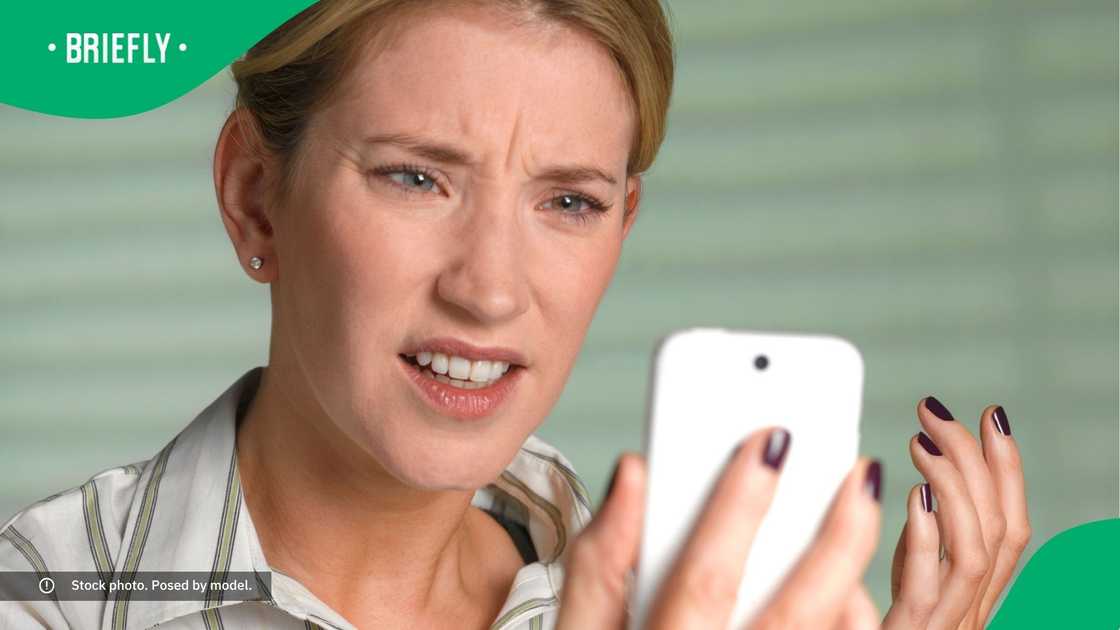 A confused woman looking at her phone.