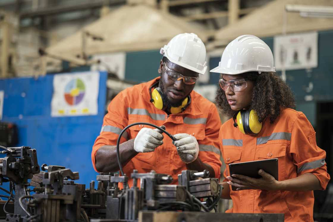 A young man and woman working on a machine. A young man and woman working on a machine.
