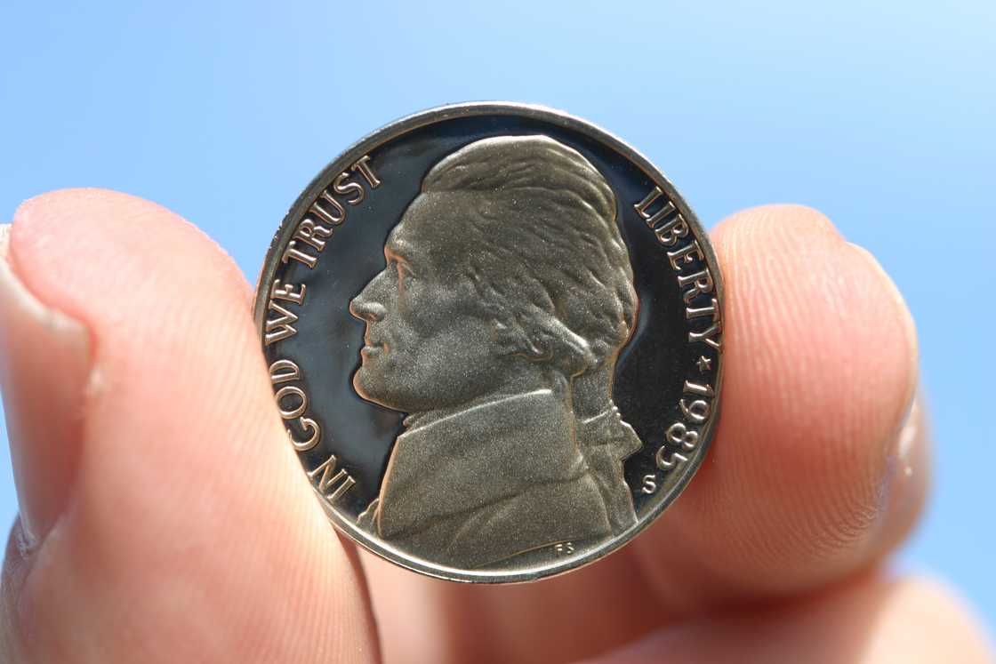 A nickel held in a hand.