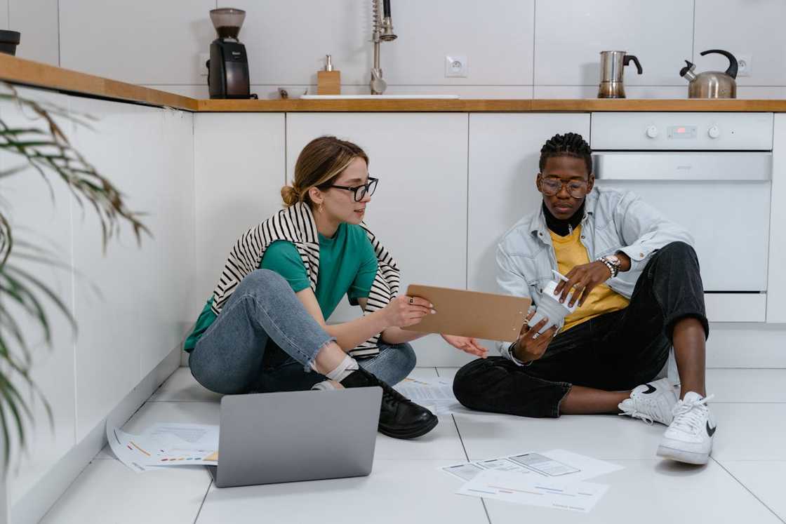 A man sits with his partner on the kitchen floor.