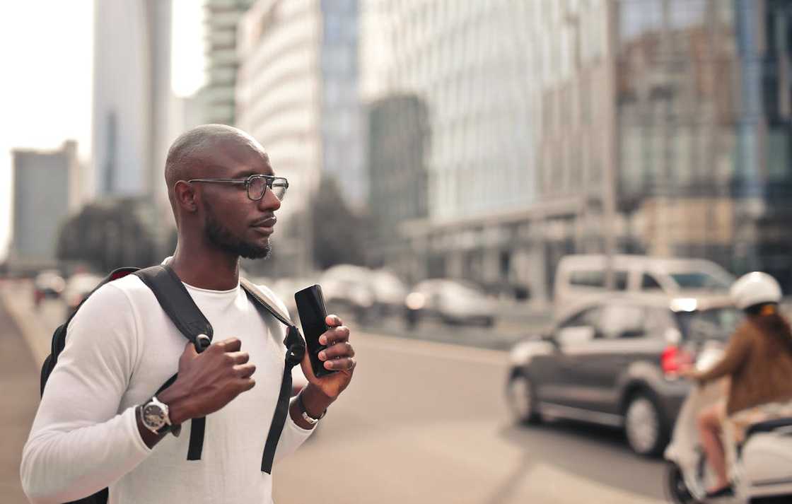 A man stands outdoors with a backpack in a busy city. A man stands outdoors with a backpack in a busy city.