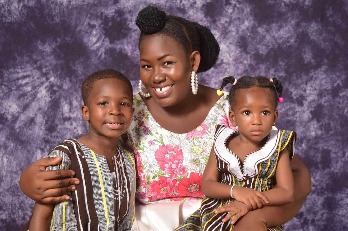 Mother posing with two young children in a studio portrait.