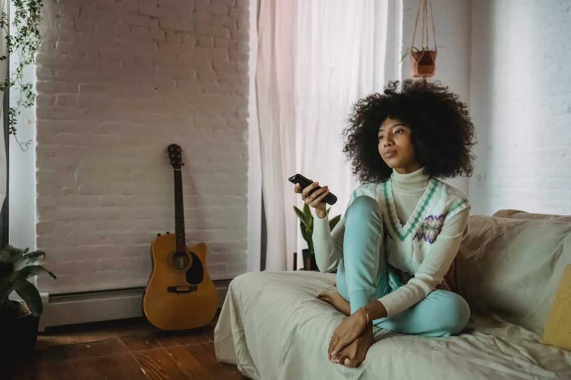 A young woman resting on the sofa and watching TV at home