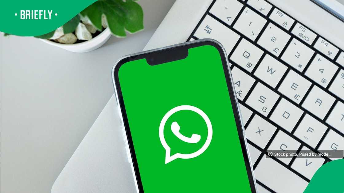 WhatsApp app icon on smartphone screen over laptop