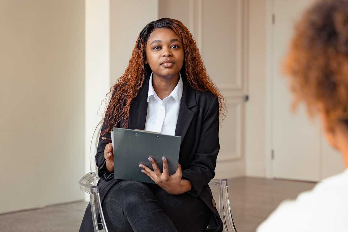 Woman holding a clipboard, listening attentively during a meeting.
