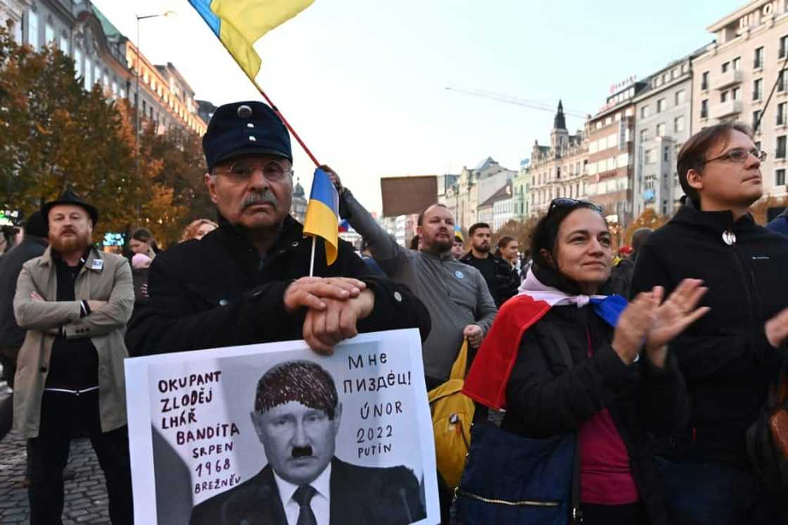 A man holds a placard reading "Occupier, thief, liar, bandit, 1968 Breznev, I'm done, 2022 Putin" depicting Russian President Vladimir Putin