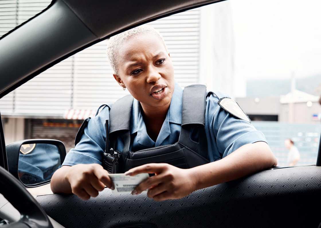 A police officer in the city talking to a driver who has violated law enforcement A police officer in the city talking to a driver who has violated law enforcement