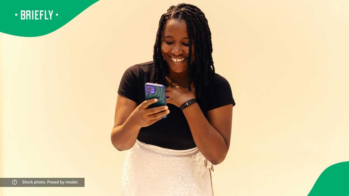 A woman smiling at her phone.